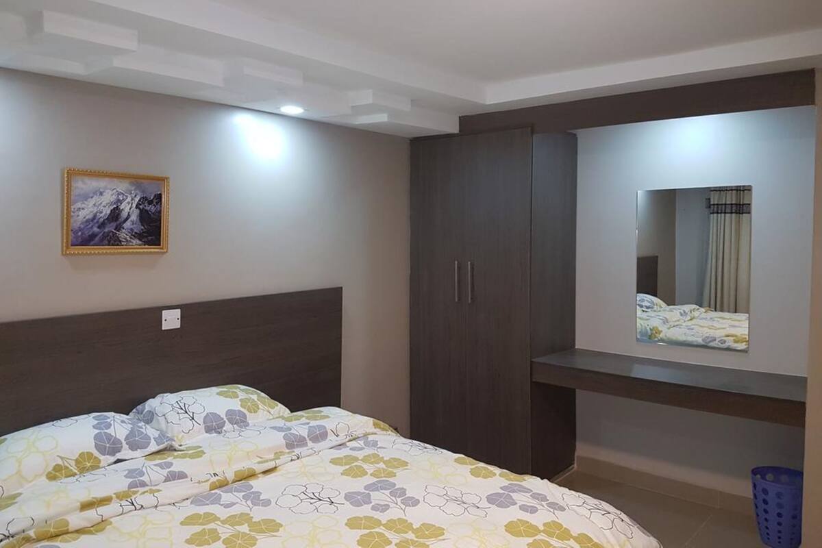 A bedroom with a bed, a wardrobe, a mirror, and a painting on the wall.