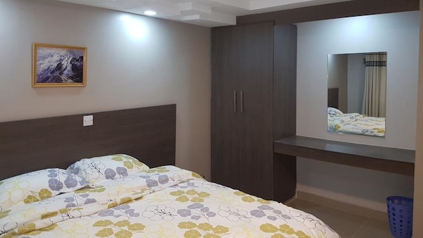Une chambre à coucher avec un lit, une armoire, un miroir et un tableau encadré accroché au mur.