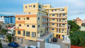 Un hotel de varios pisos con balcones, zona de estacionamiento y vistas del vecindario.