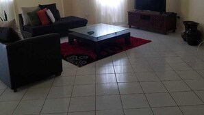 A living room with a sofa, a coffee table, a TV, and a ceiling fan. - Belle View Rising (Gros Islet)
