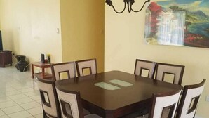 A dining area with a round table and six chairs, a chandelier, and a painting on the wall. - Belle View Rising (Gros Islet)