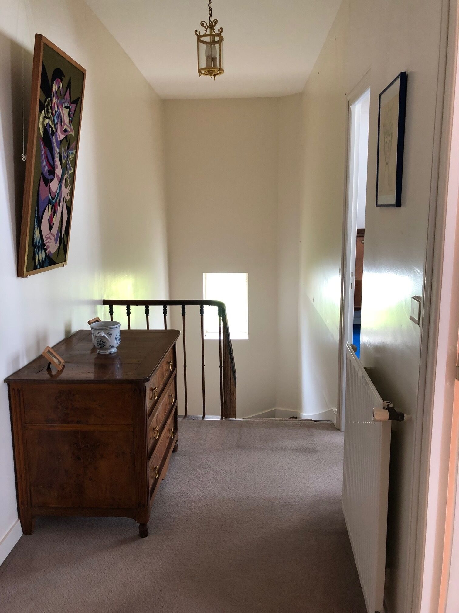 Un couloir avec une commode en bois, un tableau et un radiateur.
