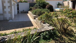 A courtyard with a paved patio, stone walls, and potted plants.
