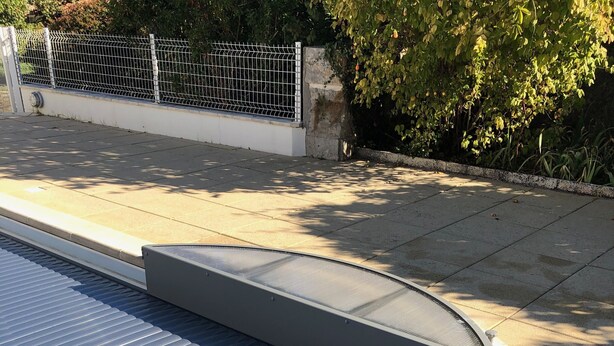 A swimming pool with a metal roof and a concrete edge.