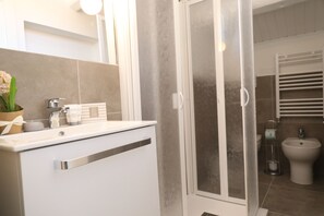 Une salle de bain moderne équipée d’une douche, de toilettes et d’un bidet.