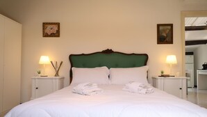 A neatly made bed with white linens and towels, two bedside tables with lamps, and framed artwork on the walls.