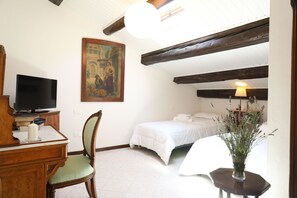 Une chambre à coucher avec un lit, un bureau avec une télévision, une chaise et un tableau accroché au mur.