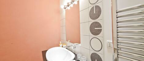 A bathroom with a white sink, a mirror, and a towel rack.