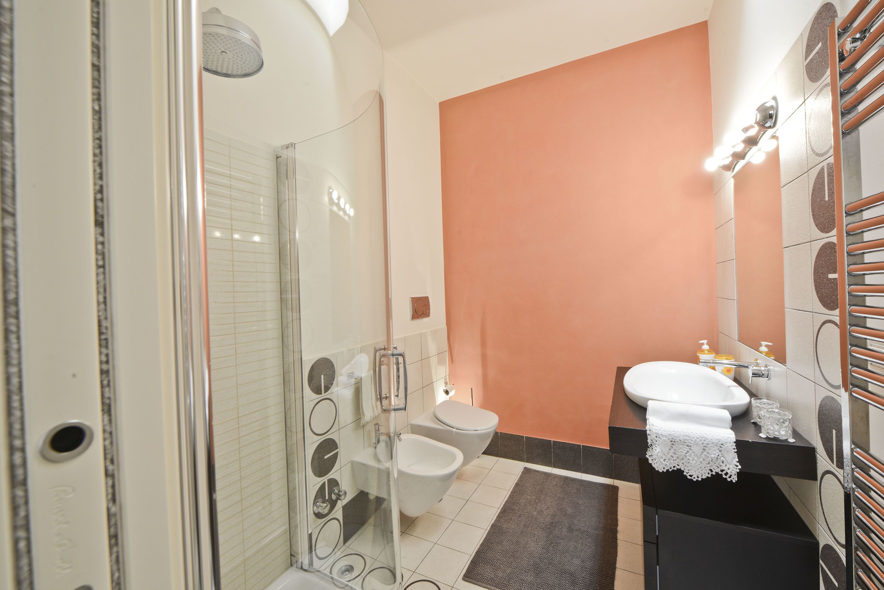 A bathroom with a glass-enclosed shower, a white toilet, and a sink with a towel.