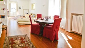 A spacious living area with a dining table, red chairs, a patterned rug, and a modern chandelier. - Appartamento Ambra con Balcone by Wonderful Italy (Ostuni)