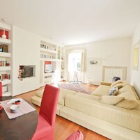 A living room with a beige sofa, a red chair, a coffee table, and a bookshelf filled with books.