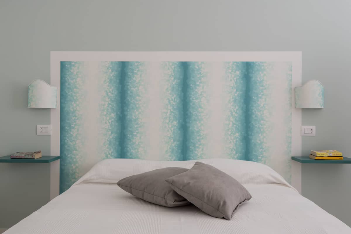 Une chambre à coucher avec un lit, deux oreillers, une tête de lit et deux tables de chevet avec des lampes.