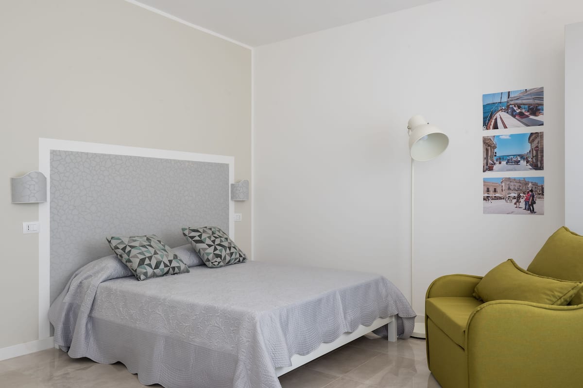 Une chambre à coucher avec un lit, une table de chevet, une lampe et un mur orné de photos.