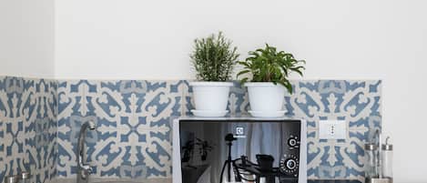 A kitchen with a modern stove, a sink, and two potted plants on the countertop.