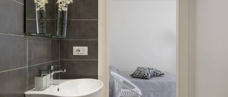 A bathroom with a white sink, two vases of white flowers, and a mirror.