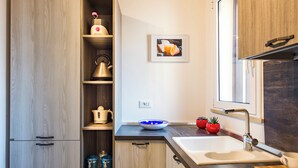 A modern kitchen with wooden cabinets, a sink, a kettle, and a bowl on the counter.