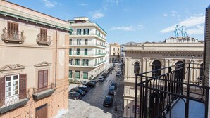 A street view with buildings, a Real Teatro Santa Cecilia, and parked cars.