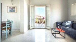 A living room with a dining table, chairs, a sofa, and a coffee table with a bottle and glasses. - Palazzo Castrofilippo Apartment by Wonderful Italy (Palermo)