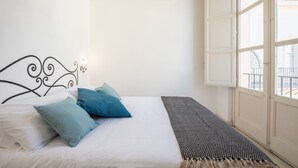 A bedroom with a bed, pillows, a window, and a door. - Palazzo Castrofilippo Apartment by Wonderful Italy (Palermo)
