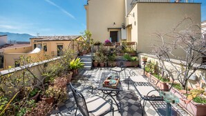 A rooftop patio with outdoor furniture, potted plants, and a view of the surrounding buildings. - Palazzo Castrofilippo Apartment by Wonderful Italy (Palermo)