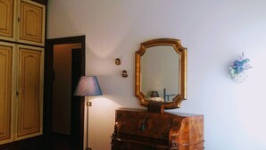 Een kamer met een houten dressoir, een spiegel, een lamp en een decoratie aan de muur.