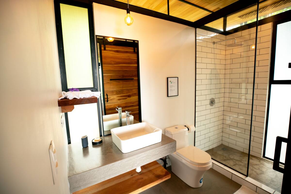 Une salle de bain moderne avec un meuble-lavabo en bois, un lavabo blanc et une douche à parois de verre.