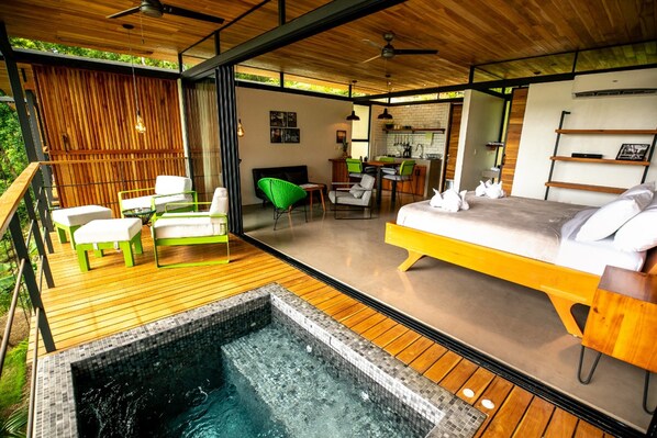 Un espacio exterior moderno con piscina, terraza de madera y una zona de estar acogedora con hamacas.