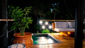A wooden deck with a hot tub, a large potted plant, and a seating area with cushions. - The Green House - Santa Teresa (Cóbano)