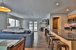 A modern kitchen with a stone backsplash, a built-in microwave, and a large island with stools. - The Big Chillington Sleeps 6 in Killington Center (Killington)