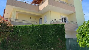 A two-story building with a balcony on the upper floor, a door on the ground floor, and a small window on the upper floor. - A 3-floor Building With 4 Bedroom, Near Beach (Dërmenas)