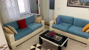 A living room with two sofas, a coffee table, and two ottomans. - A 3-floor Building With 4 Bedroom, Near Beach (Dërmenas)