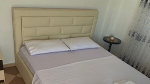 A bed with a headboard, two pillows, and a neatly folded white towel on the bed. - A 3-floor Building With 4 Bedroom, Near Beach (Dërmenas)