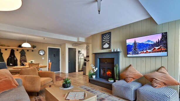 A modern living room with a fireplace, sofas, and a television. - The One Everyone Wants in Building 3 at Mountain Green: 1BR, Newly Renovated! (Killington)