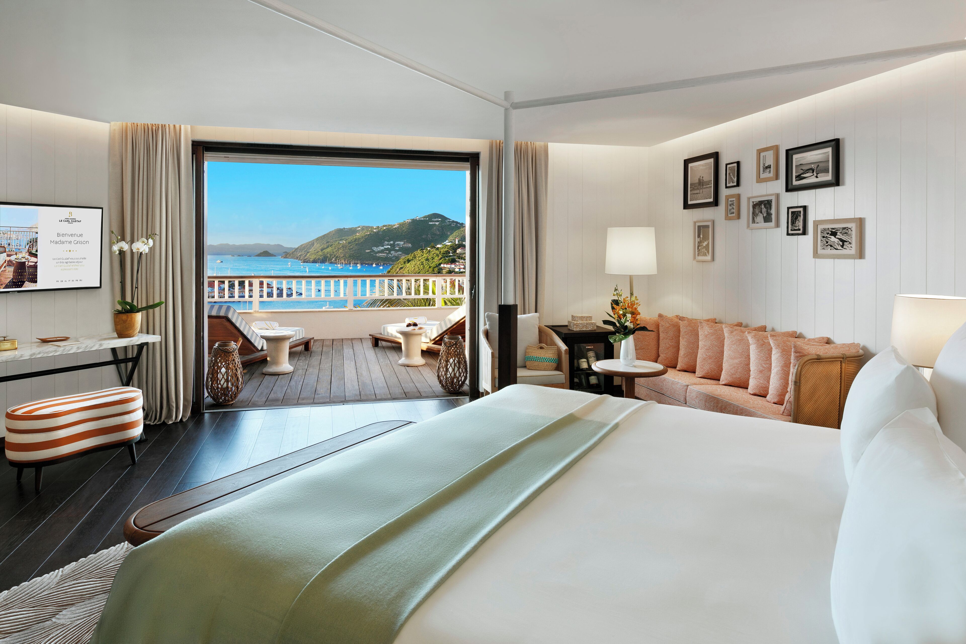 A hotel room with a bed, a sofa, a desk, and a view of the sea.