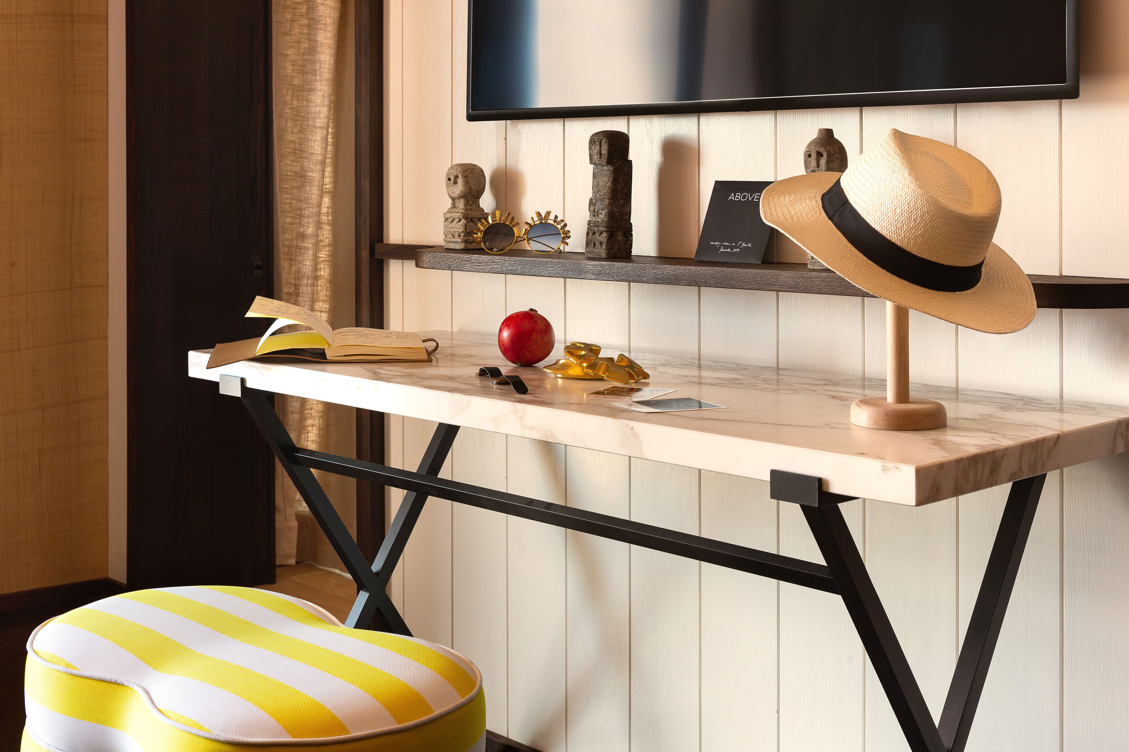 A study area with a desk, books, a hat, and decorative items.