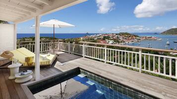 A pool area with a view of the ocean and a town.