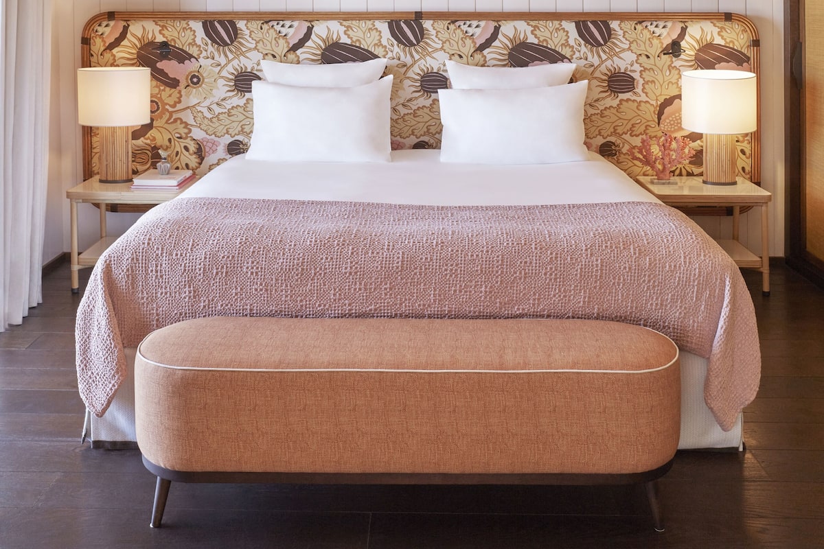 Ein Schlafzimmer mit einem großen Bett, zwei Nachttischen, einer Bank und einer Decke mit Holzbalken.