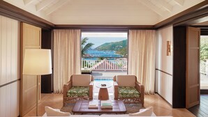 Une chambre avec vue sur une piscine et des montagnes, comprenant deux fauteuils, une table et une lampe.