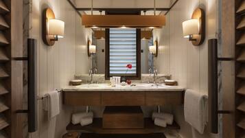 Un baño moderno con tocador de doble lavabo, encimeras de mármol e iluminación empotrada.