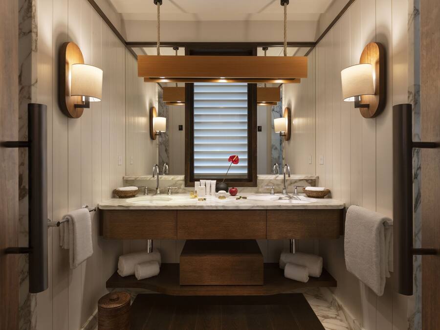 Un baño moderno con tocador de doble lavabo, encimeras de mármol e iluminación empotrada.