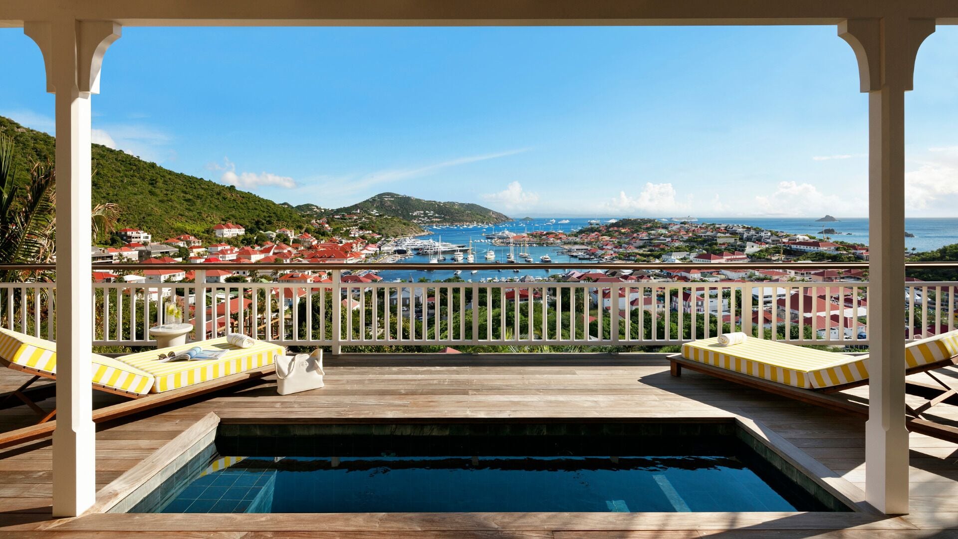 A pool area with a view of a marina and town.