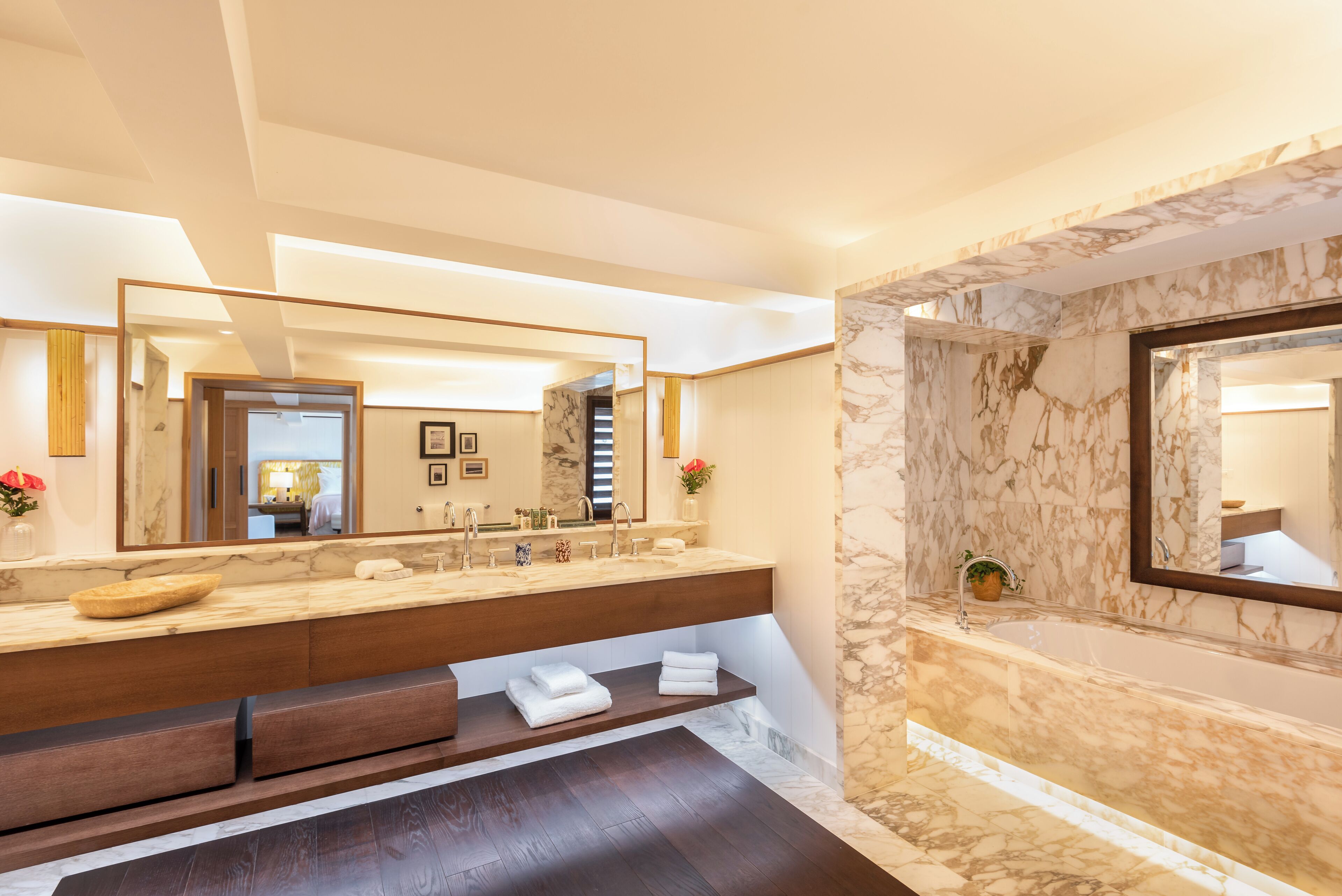Ein modernes Badezimmer mit Waschtisch aus Marmor, zwei Waschbecken, einem großen Spiegel und einer Badewanne.