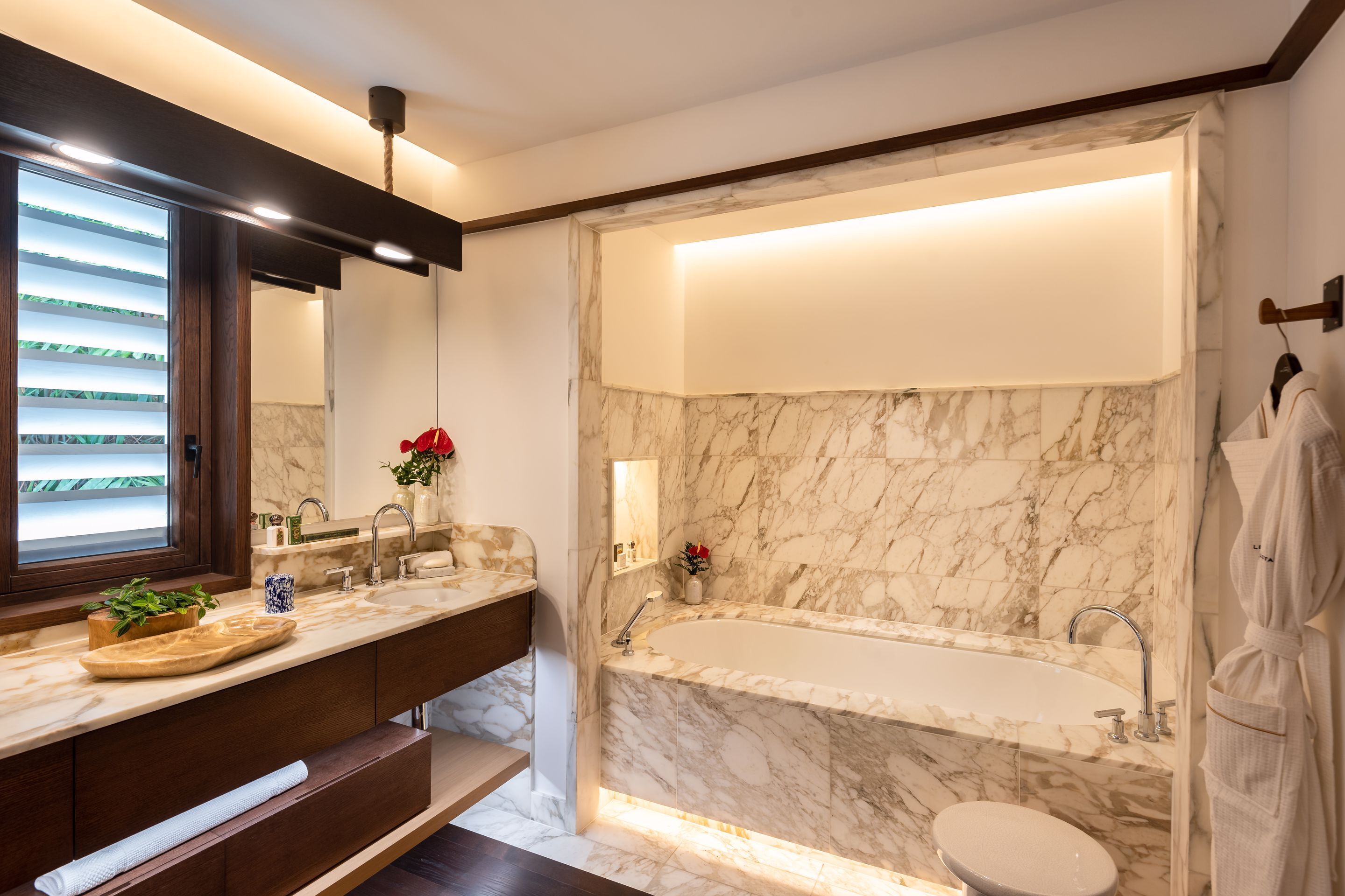 A modern bathroom with a marble sink, a bathtub, and a toilet.