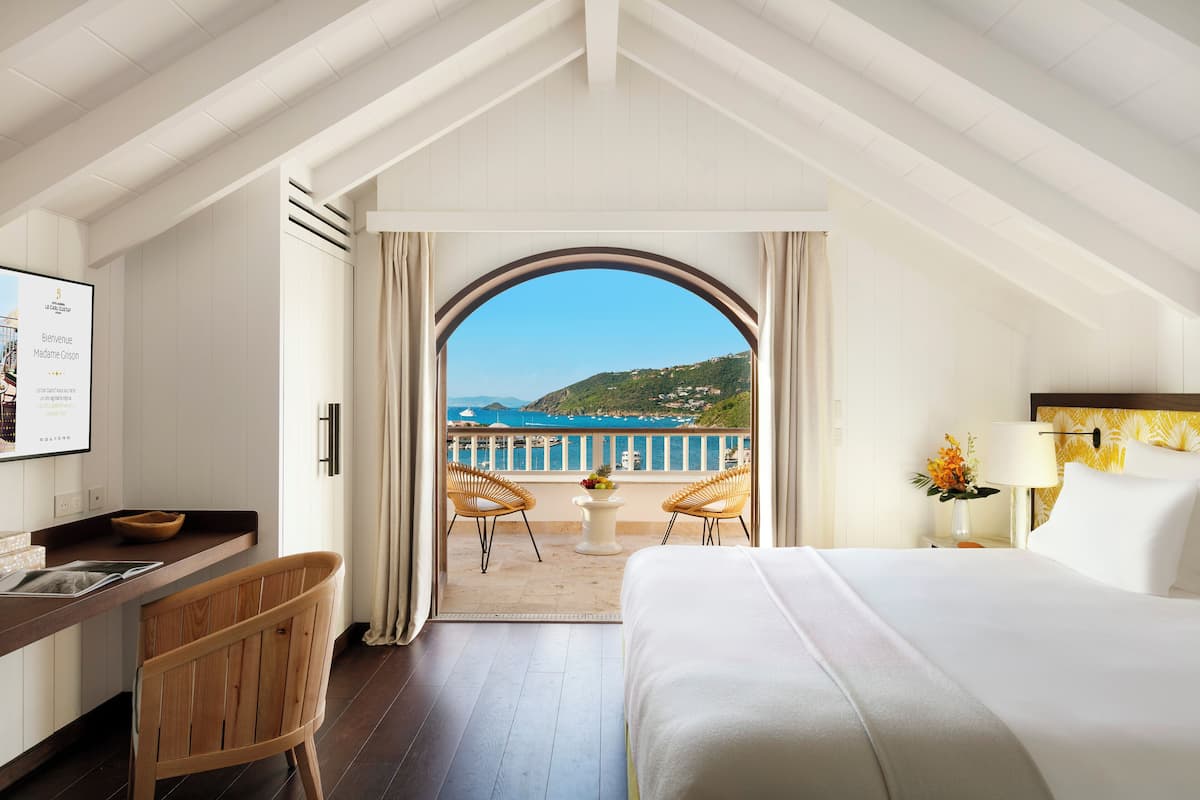 Ein Hotelzimmer mit Bett, Schreibtisch und Balkon mit Sitzgelegenheiten.