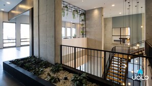 Un interior moderno con escalera de hormigón, barandilla metálica y plantas colgantes.