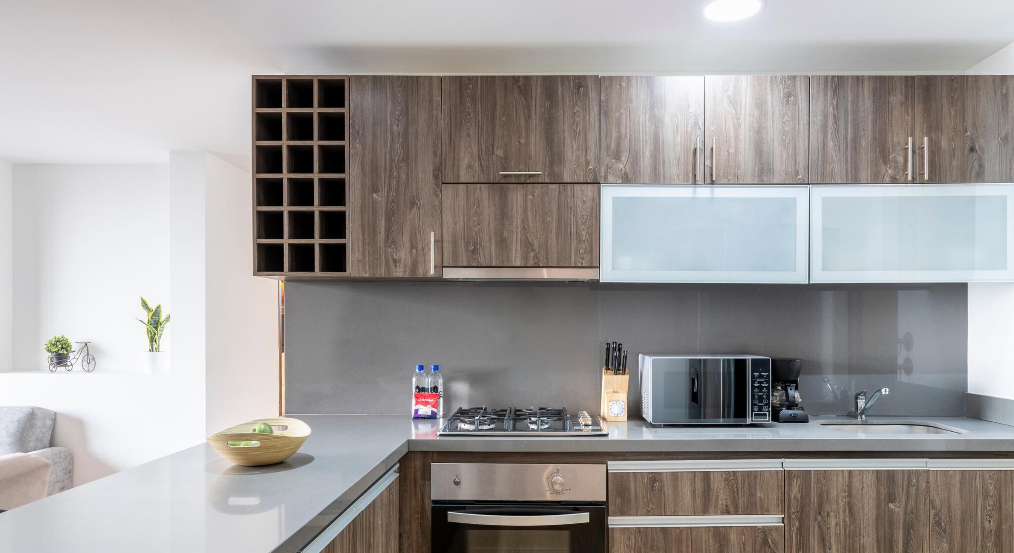 Een moderne keuken met houten kastjes, een ingebouwde magnetron en een gasfornuis.