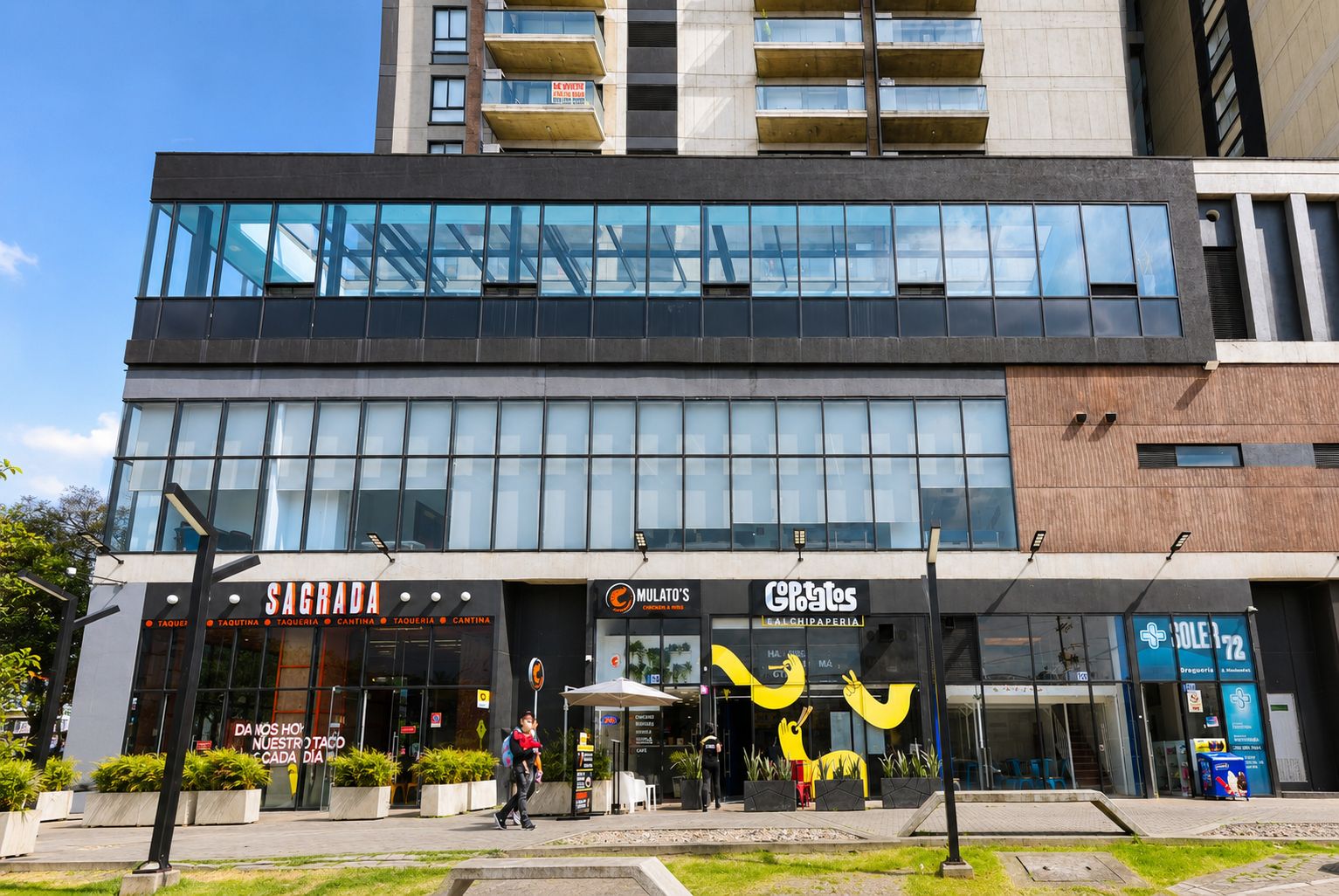 A modern building with a glass facade, storefronts for 'SAGRA' and 'MULATO'S', and a 'GOPOTOS' sign.