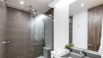 A modern bathroom with a glass shower enclosure, a wooden vanity, and a large mirror.