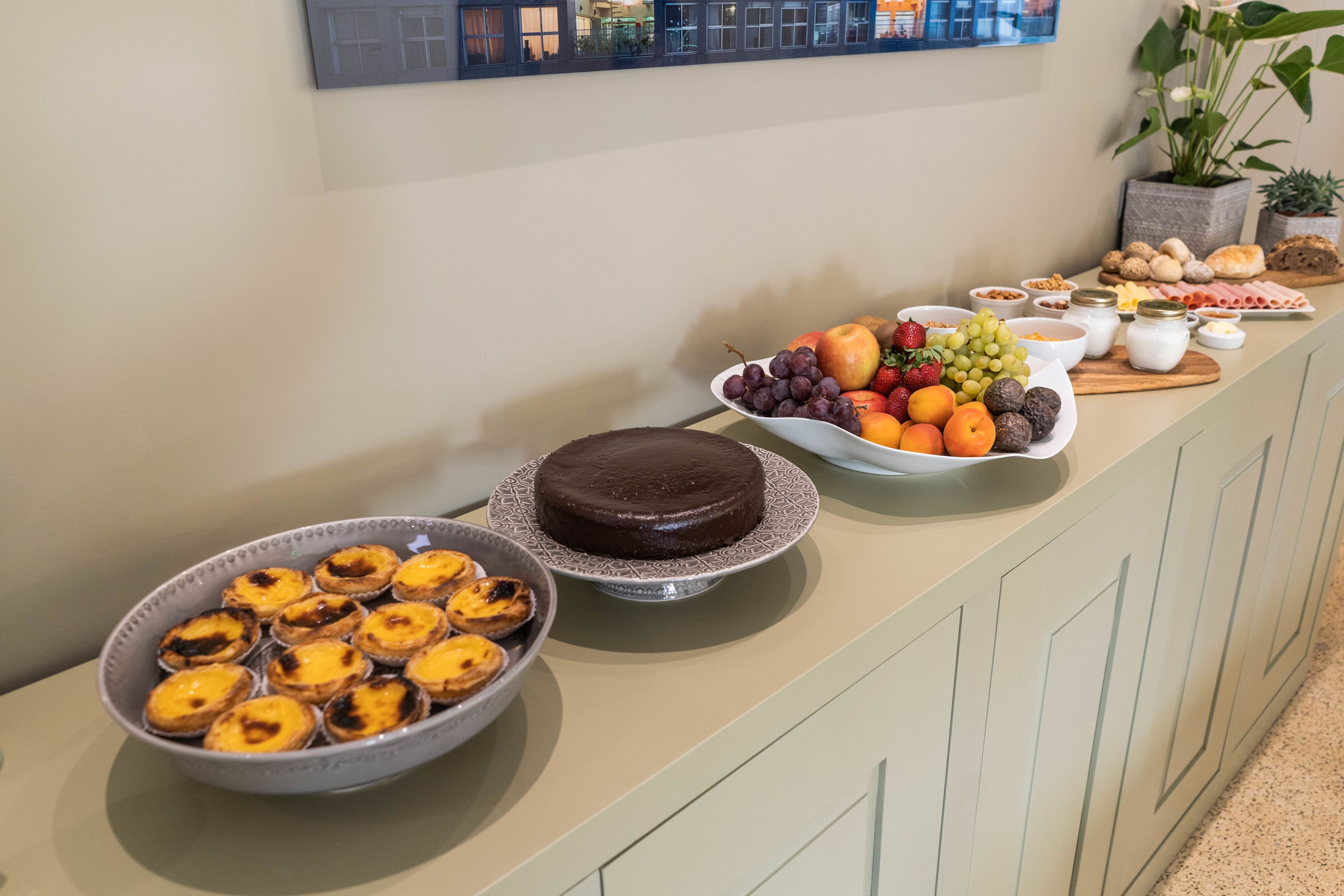 Una mesa de buffet con diversos alimentos, incluyendo pasteles, frutas y un pastel de chocolate.