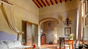 A spacious bedroom with a large bed, a wooden desk, and a chair. There is a mirror, a chandelier, and a door leading to another room. - Villa Gerlino - Country House with private pool (Rapale)